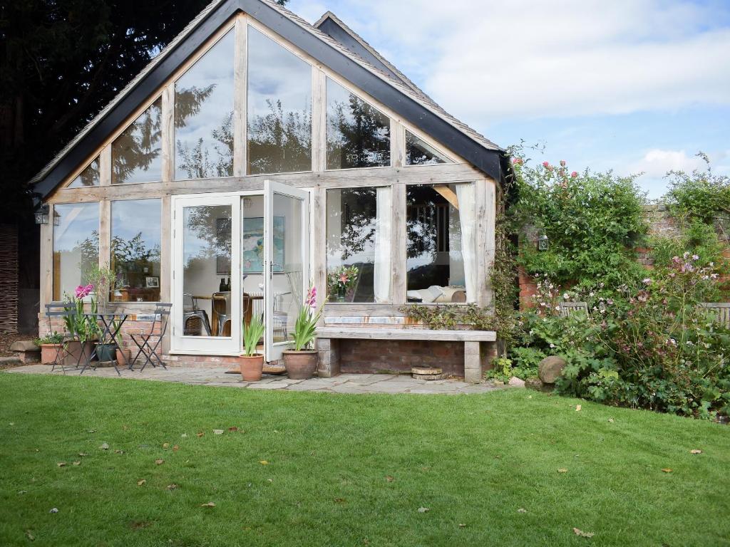 a glass house with a bench in a yard at The Garden Retreat in Marbury