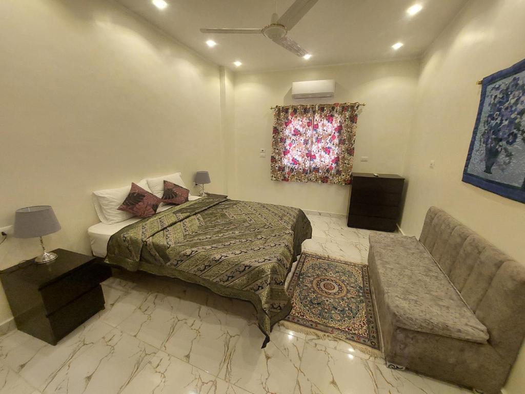 ein Schlafzimmer mit einem Bett und einer Couch und einem Fenster in der Unterkunft Carter Guesthouse Luxor 2 in ‘Ezbet Abu Ḥabashi