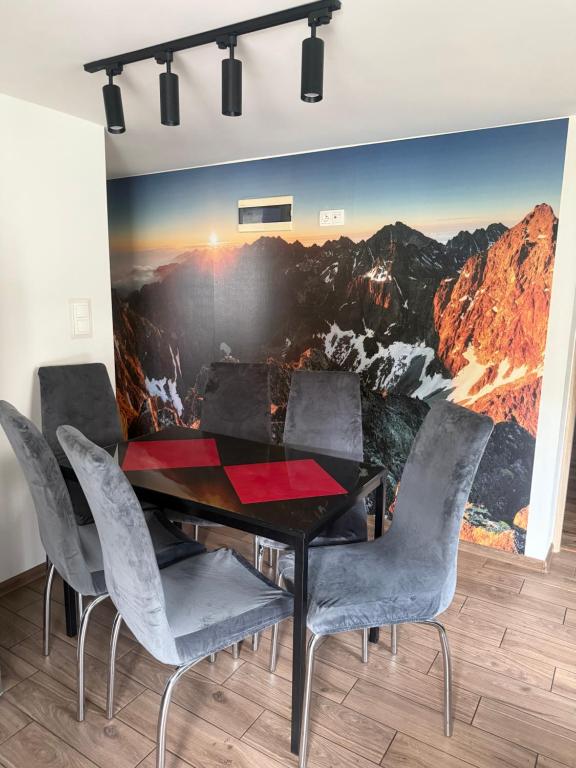 a dining room with a table and chairs with a mountain mural at Apartament przy plaży in Międzybrodzie Żywieckie