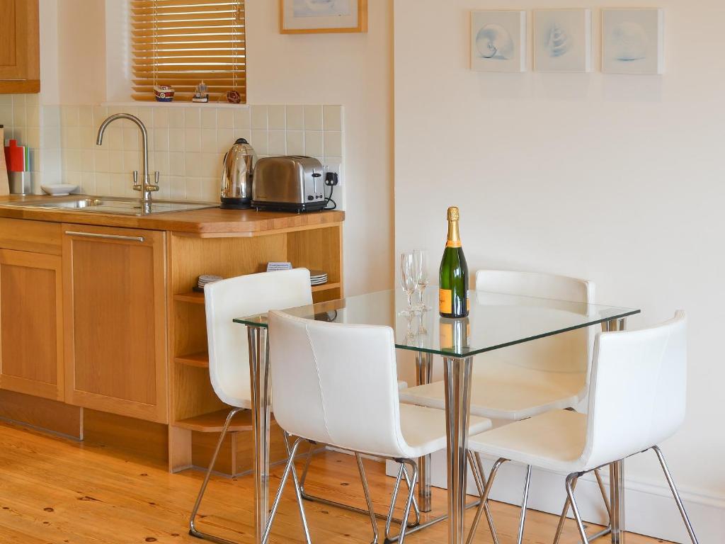 a glass table with white chairs and a bottle of wine at Tides Reach in Fowey