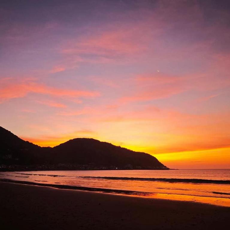 伊東市にあるIG2 源泉掛け流し温泉付きの宇佐美貸切宿 お宿 喜喜哀楽 Oyado Kikiairakuの山を背景に海辺の夕日