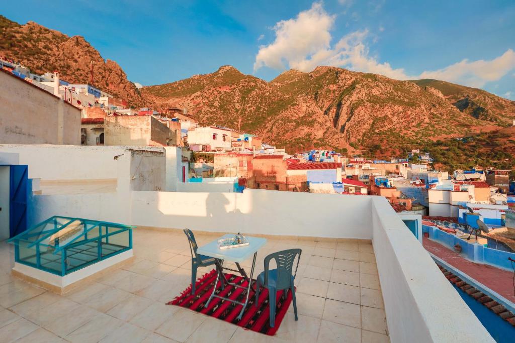 a table and chairs on a balcony with a view of a city at Dar Daarama in Chefchaouene