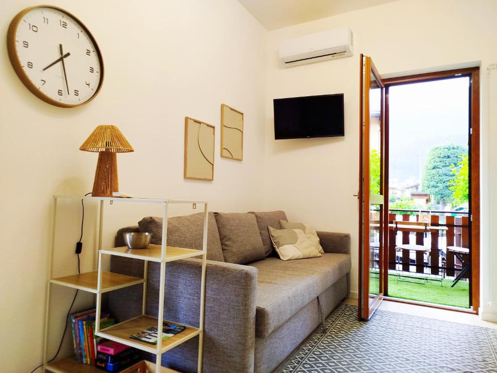 a living room with a couch and a clock on the wall at Holiday house in Rovetta