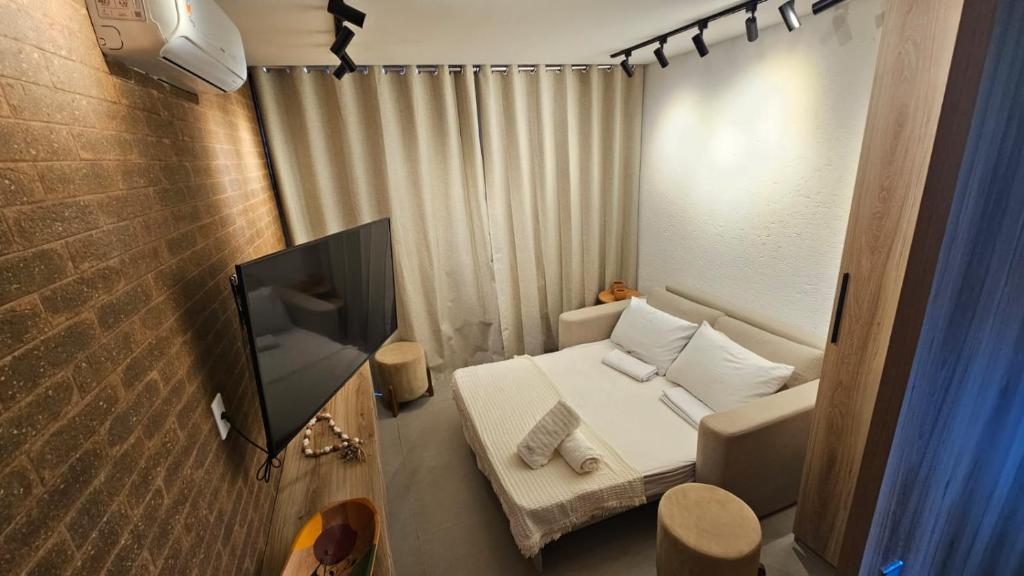 a small room with a bed and a flat screen tv at Apt com piscina e sauna privativo em Milagres, Praia do Riacho in São Miguel dos Milagres