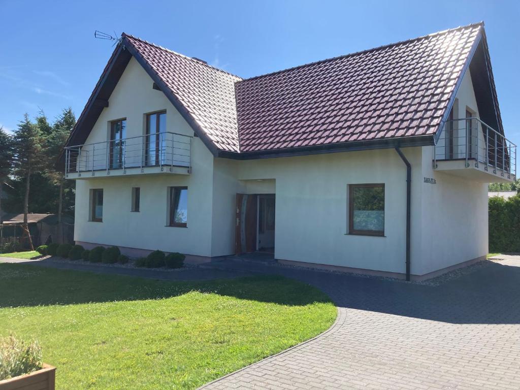 a white house with a metal roof at Sielska Chatka in Sarbinowo