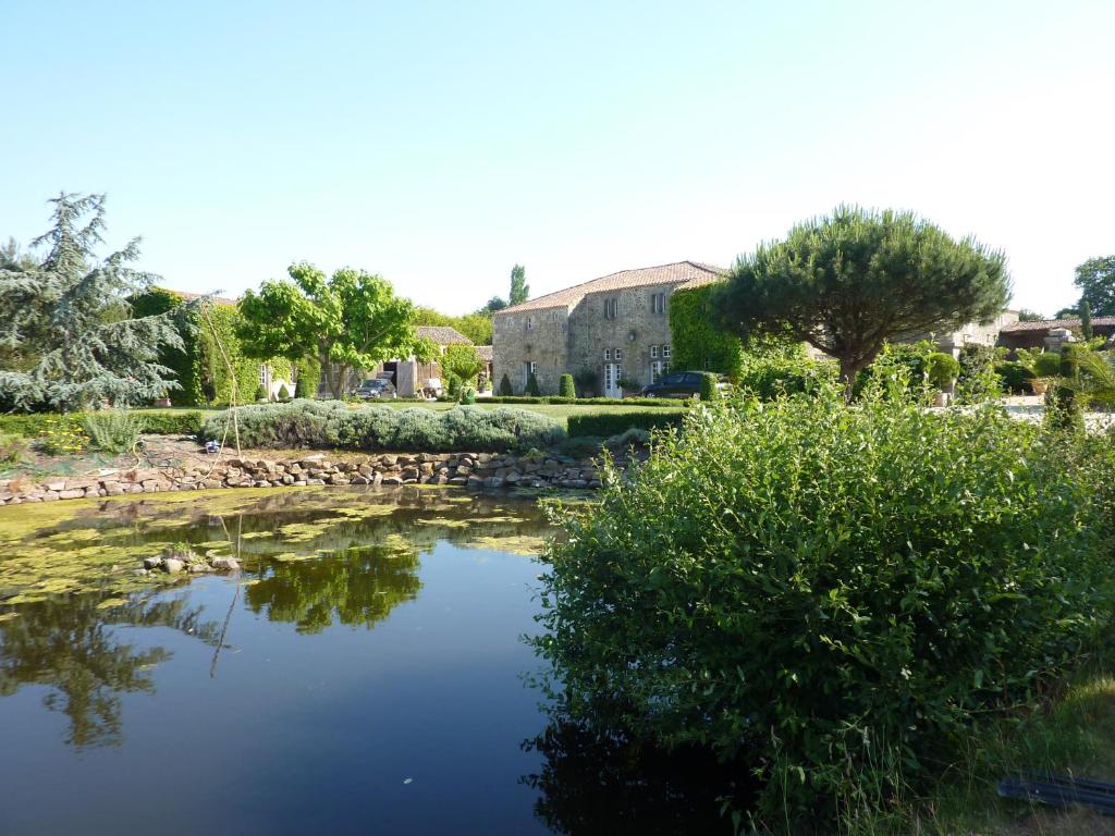 Landevieille的住宿－Logis de la Robliniere，一座花园,在一座建筑前设有一个池塘