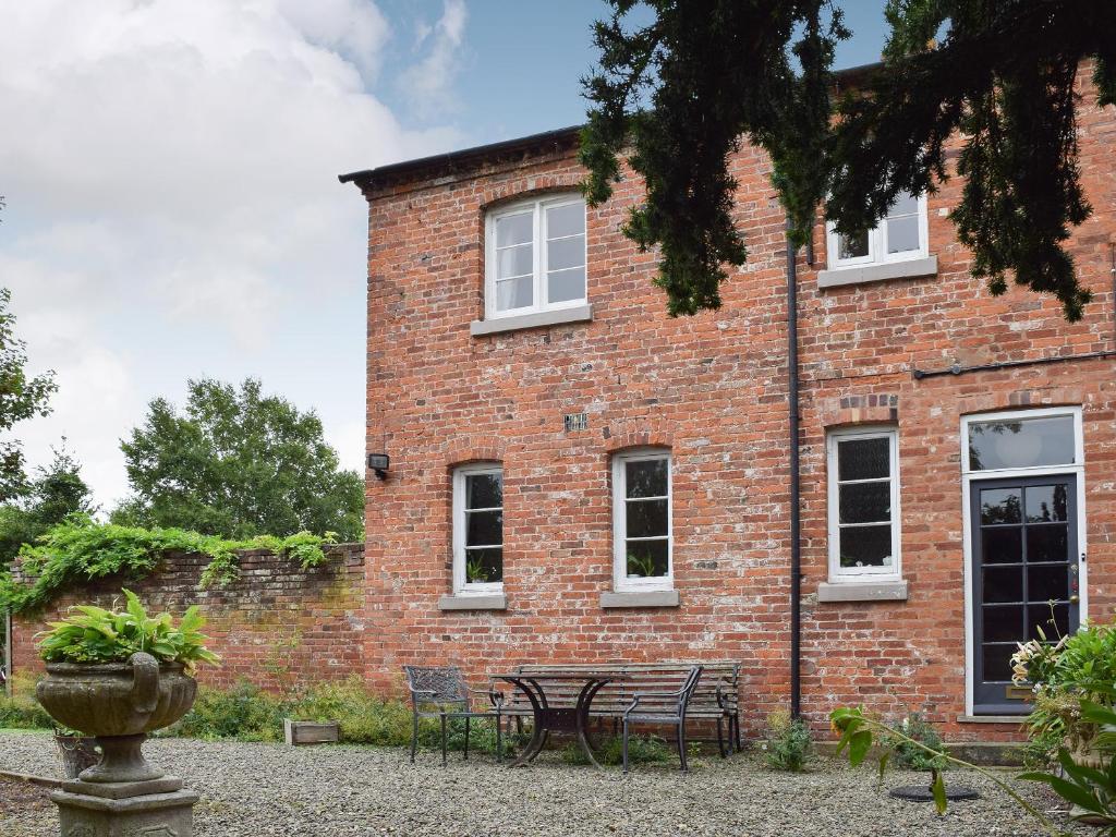 un edificio de ladrillo con una mesa y sillas delante de él en Wisteria Loft-24773, en Tenbury