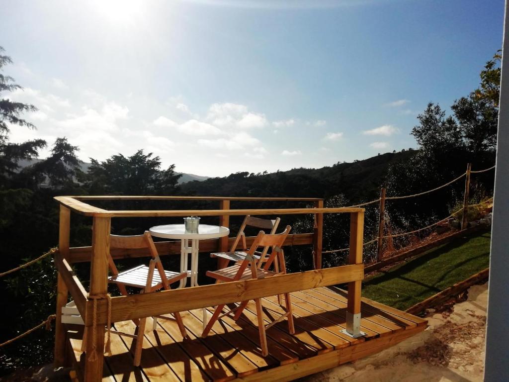a wooden deck with a table and two chairs at Sunset Little House in Aljezur