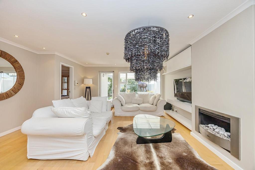 a living room with white furniture and a chandelier at The Island Beach Villa in Cape Town