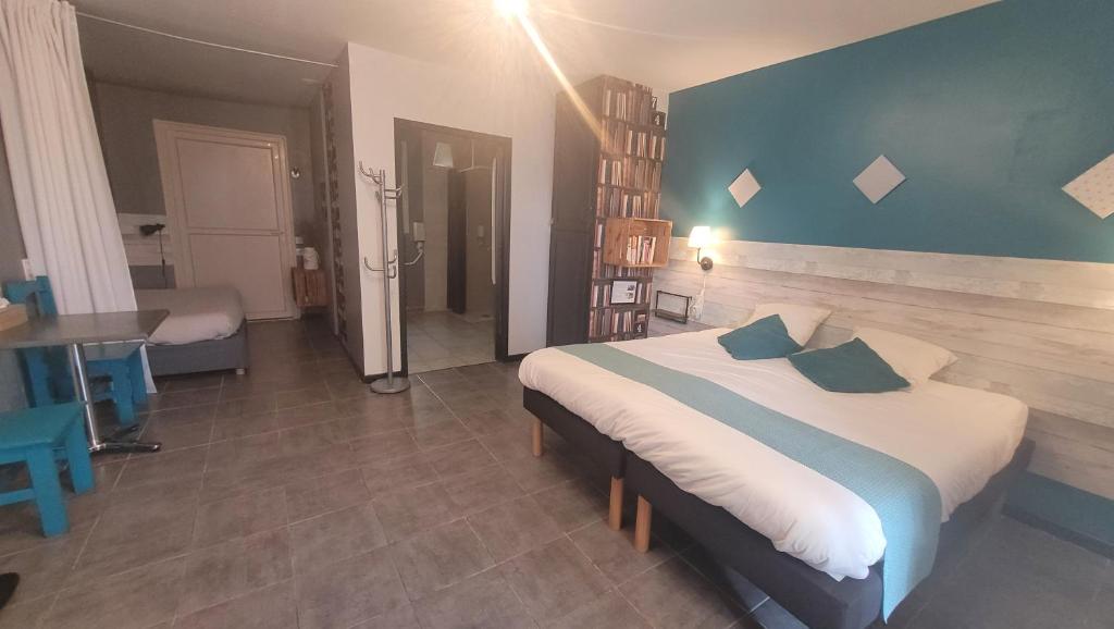 a bedroom with a large bed with a blue wall at Hotel La Peyrade in Cajarc