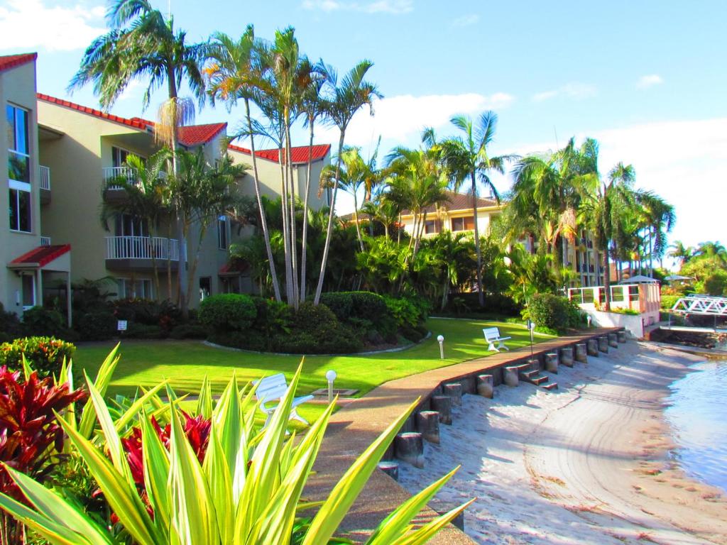a resort with palm trees and a walkway next to the water at Bayview Waters Apartments in Gold Coast