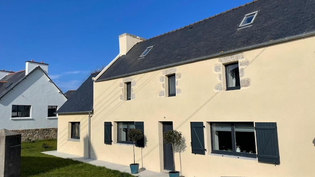 une maison blanche avec un toit noir dans l'établissement Bleiz Mor, à Brignogan-Plage
