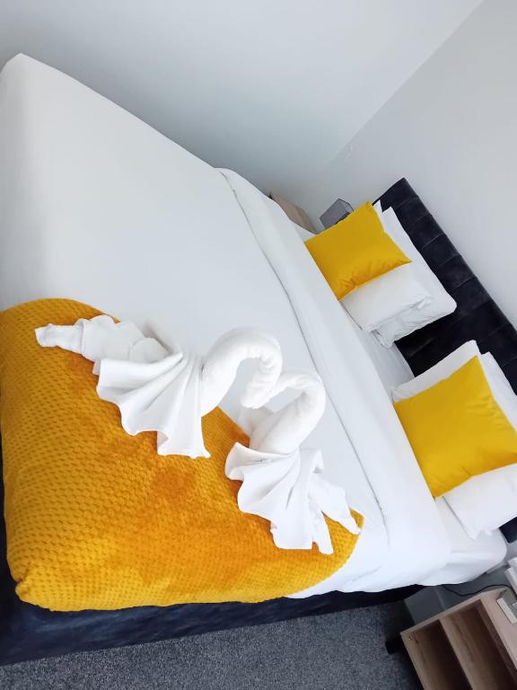 a bed with white sheets and yellow pillows at Spectacular London Stay in Crystal Palace