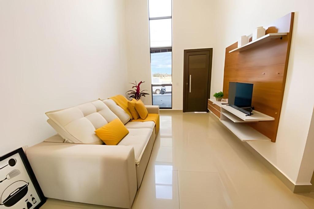 a living room with a white couch and a television at Linda Casa com 2quartos para 5 pessoas in Foz do Iguaçu