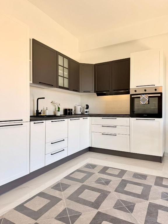 een witte keuken met witte kasten en zwarte apparaten bij La casa delle parole 2 in Agrigento
