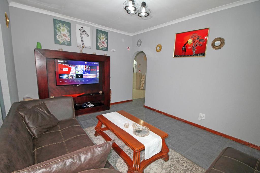 a living room with a couch and a tv at Comfortable 4 Bedroom Flat in Germiston with WI-FI in Germiston