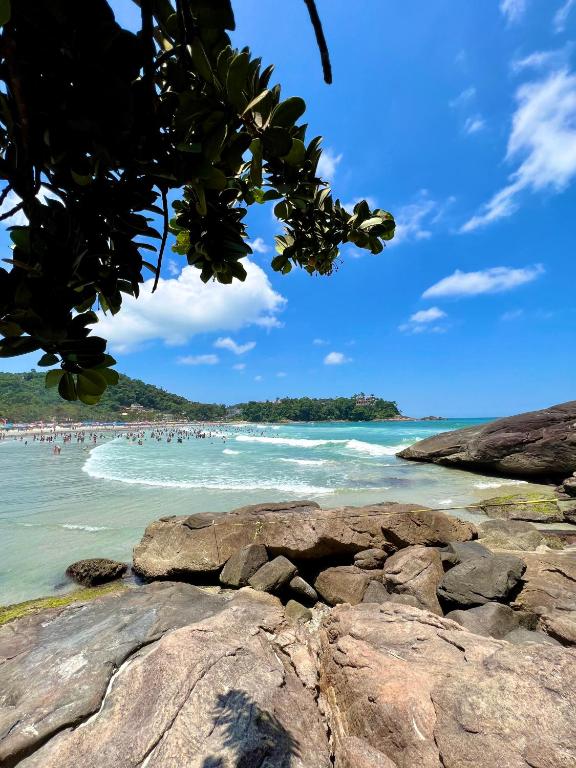 a beach with people in the water and rocks at Pousada Serrate in Ubatuba