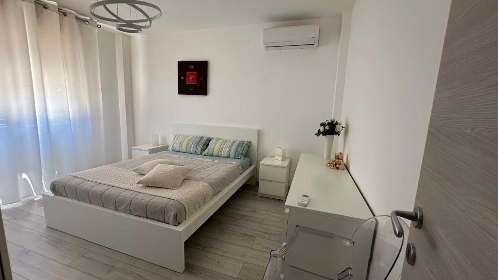 Un dormitorio blanco con una cama y un escritorio. en Appartamento Su Planu IUN R5007, en Pirri