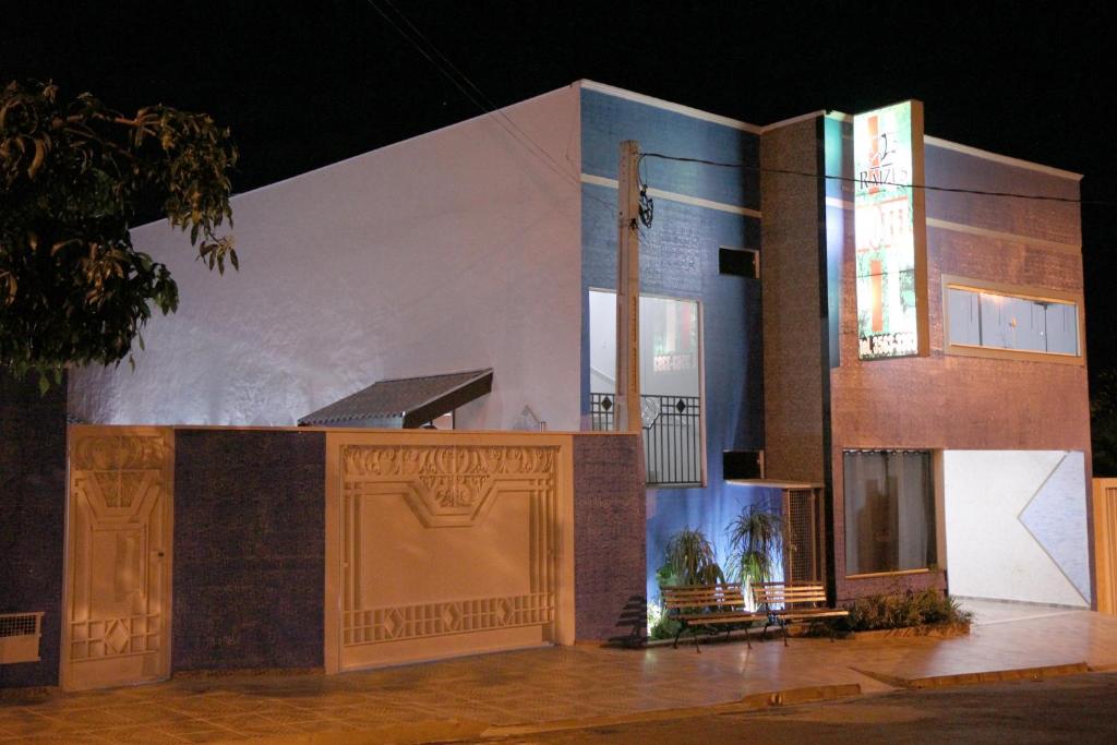 a large white building with a gate in front of it at Raízes Hotel in Cajobi