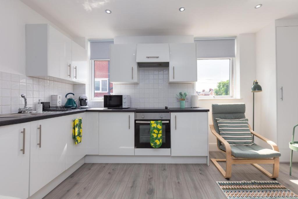 a kitchen with white cabinets and a chair in a room at Lytham St Annes Luxury Apartment - No 1 Tides Reach in Lytham St Annes
