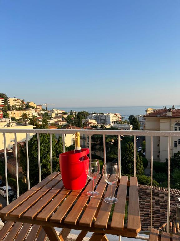 - une table en bois avec 2 verres à vin sur le balcon dans l'établissement Appartement Vue Mer T2 Cosy, Plage à pied 3 mins, Coucher de Soleil, Parc privé, à Nice