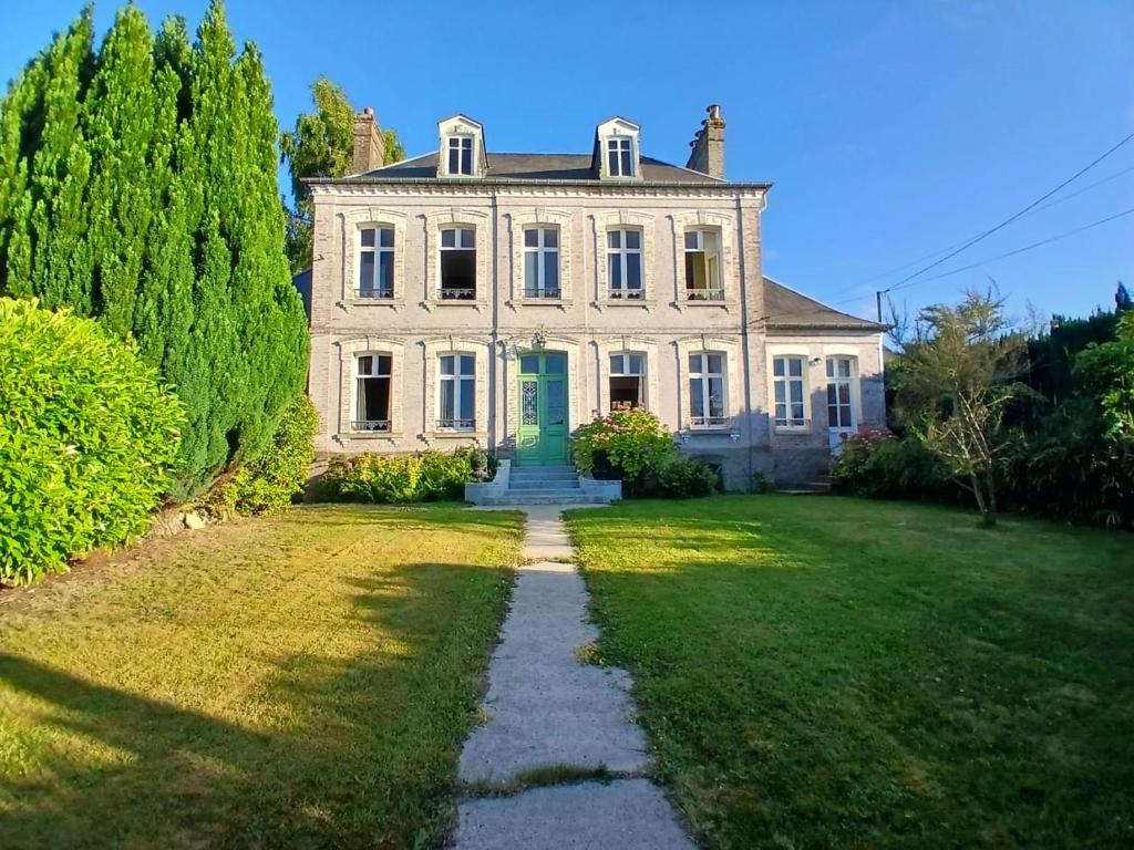 une grande maison blanche avec une porte verte dans une cour dans l'établissement Belle demeure a 10 min de la mer, à Woincourt
