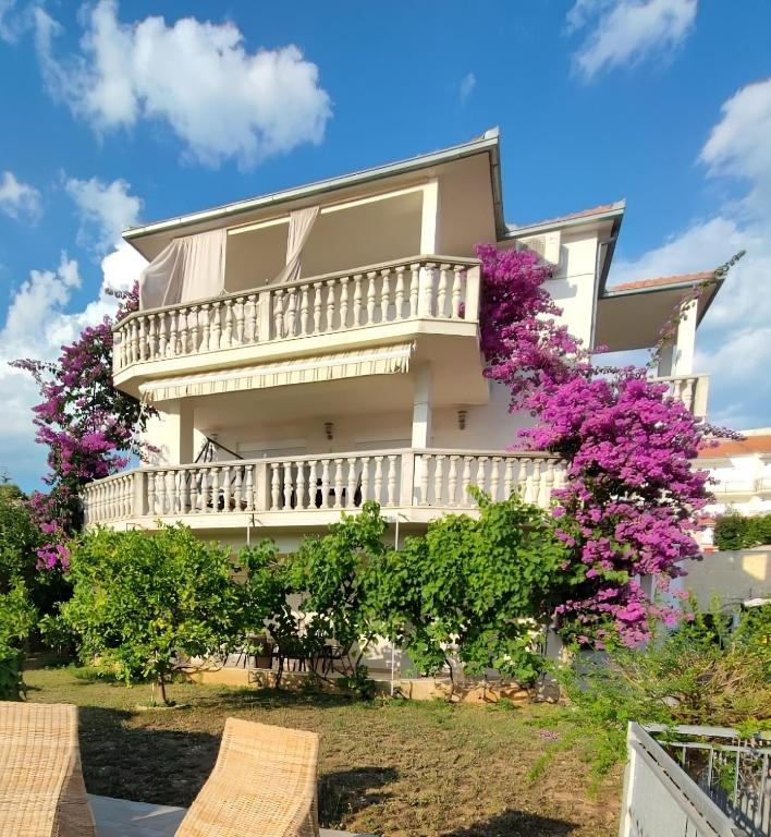a large house with a balcony and purple flowers at Apartmani Jureta in Okrug Gornji