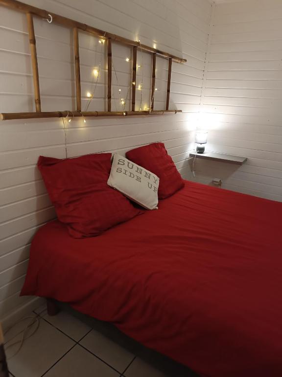a bed with a red blanket and two red pillows at Chez RAM'S in Le Tampon