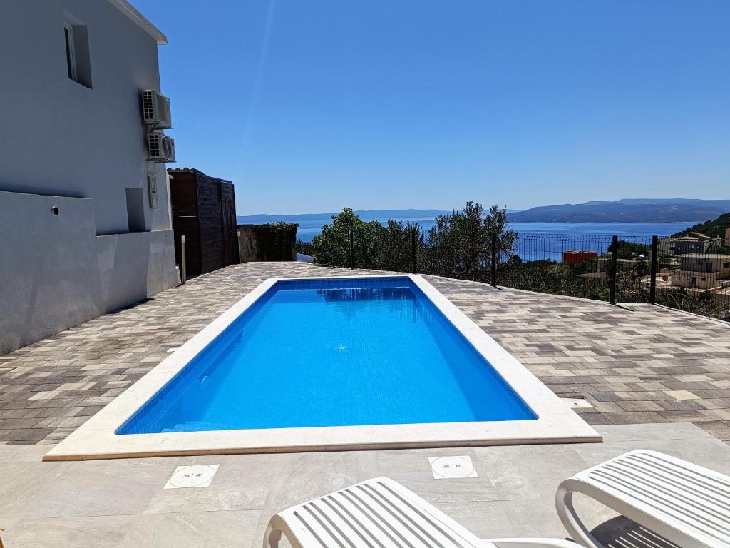 a blue swimming pool on a patio with two chairs at Villa TOP HILL with Private Pool in Makarska