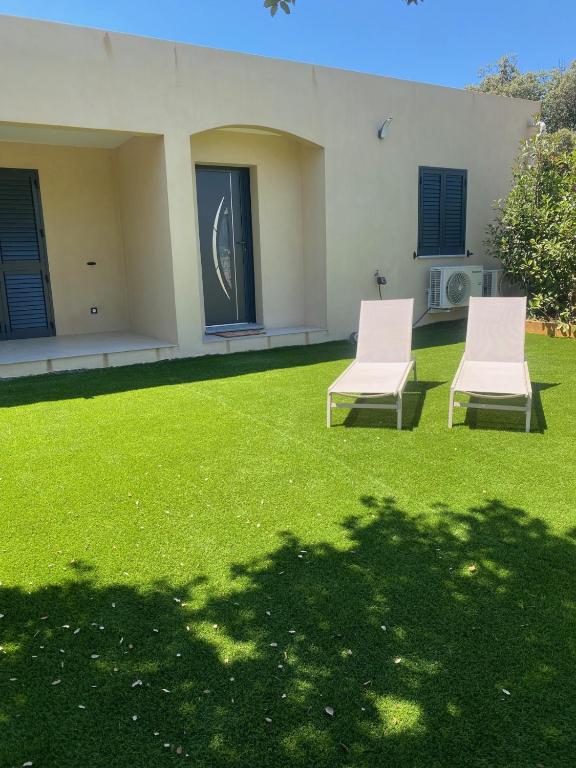 deux chaises assises sur une pelouse devant une maison dans l'établissement Villa CALLINAJO , à 1 min de la plage LOZARI, à Belgodère