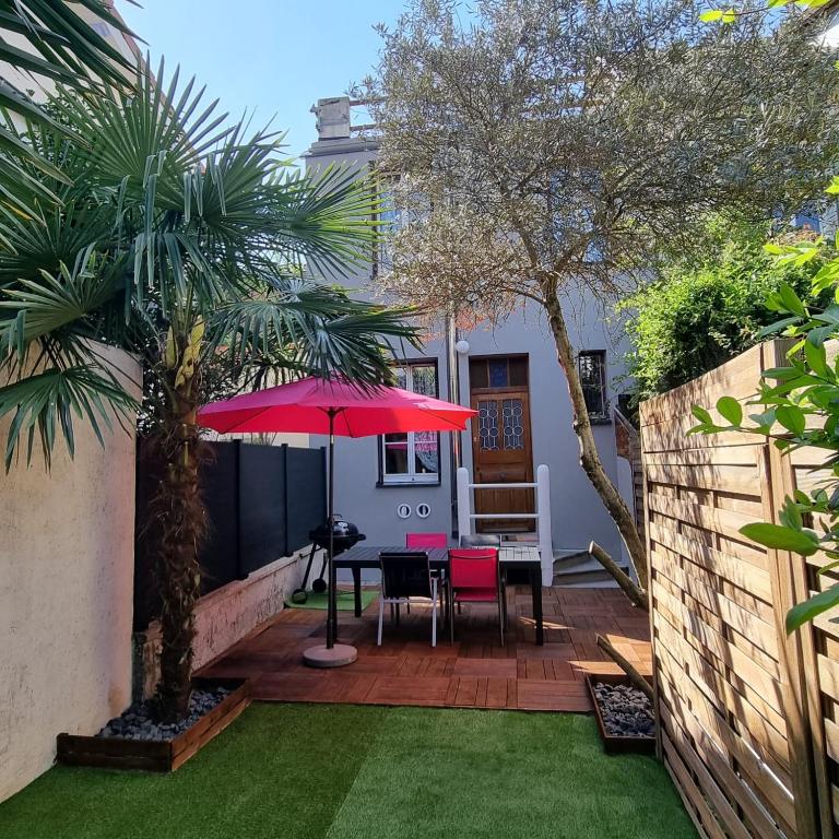 a patio with a table and a red umbrella at Maison charmante, années 30 avec extérieur à l'Ile Verte in Grenoble