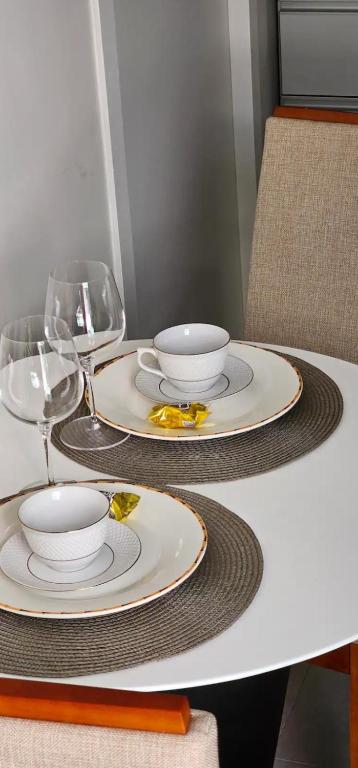 a table with two plates and wine glasses on it at Lugar Aconchecante 2 Ap 102 in Palhoça