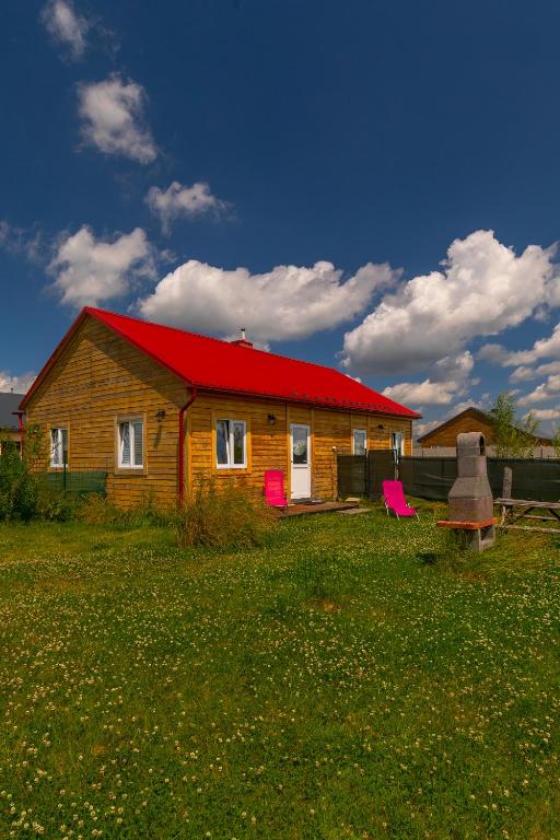 a house with a red roof and two pink chairs at Karkonoskie Sny - Domki z widokiem na Karkonosze in Wojcieszyce