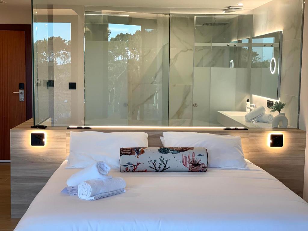 Un dormitorio con una cama blanca con dos toallas encima. en Hotel Delfin Azul, en A Lanzada