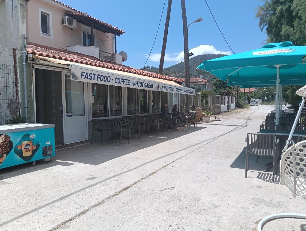 a first floor coffee shop with tables and an umbrella at ΤΑ ΩΡΑΙΑ ΤΗΣ ΑΘΗΝΑς in Skala Mistegnon