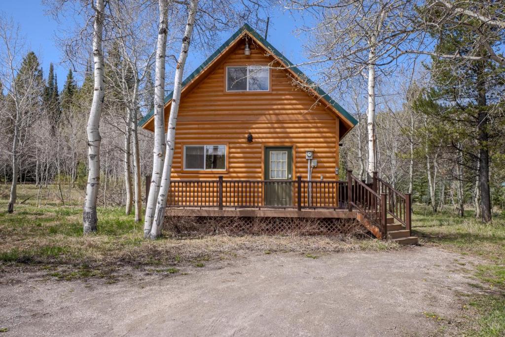 a log cabin in the woods with a porch at The Aspen House in West Yellowstone