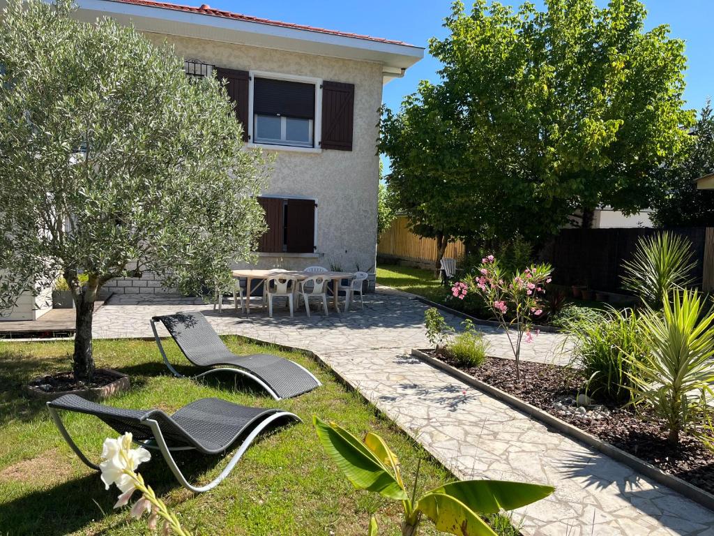 un jardin avec deux chaises et une table devant une maison dans l'établissement La Bergeronnette, à Ondres