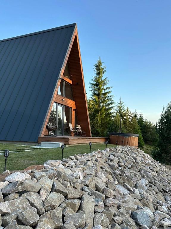 a house with a black roof on top of a pile of rocks at Monteluce Aframe in Mărişel