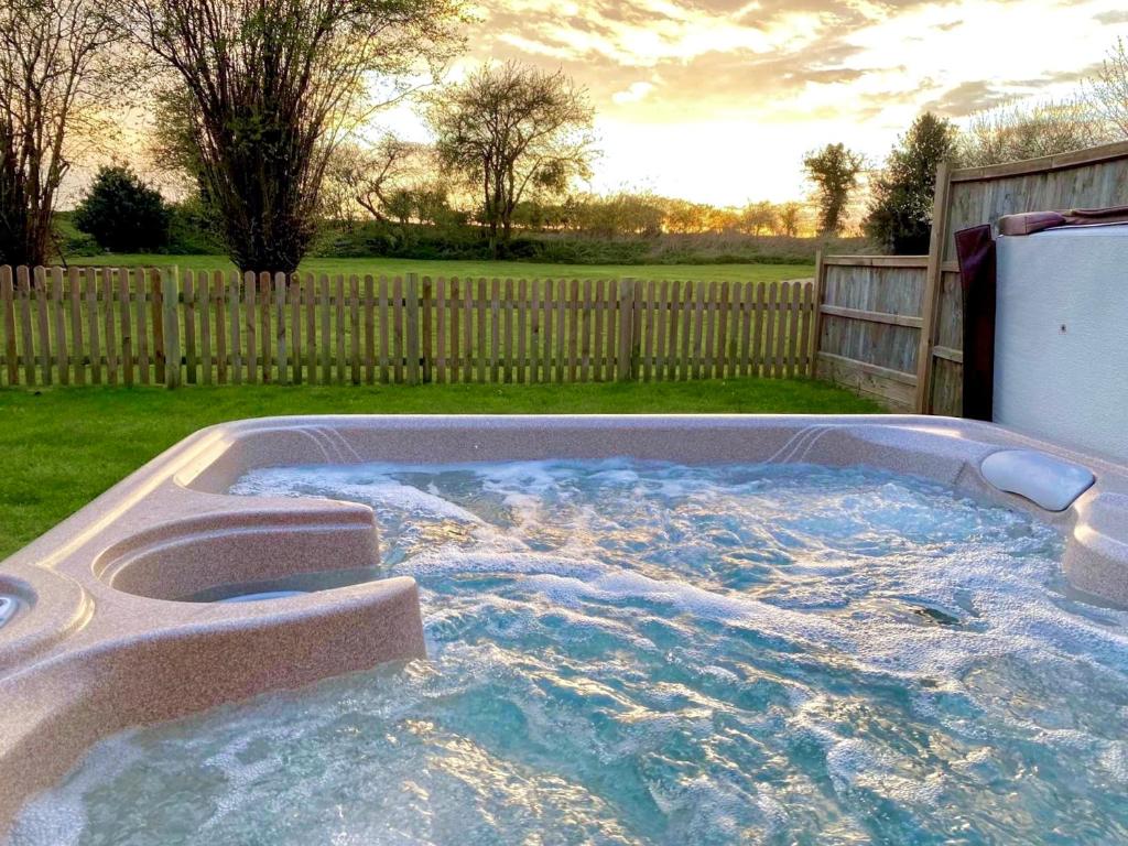a hot tub in a yard with a fence at Brick Kiln Barns in North Walsham