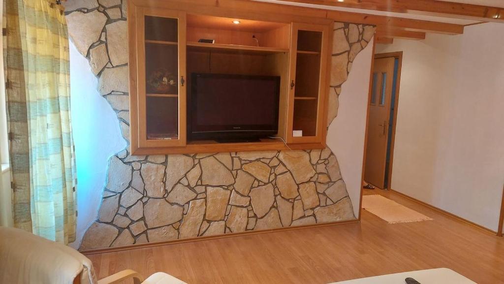 a living room with a tv and a stone wall at Family apartment in old town in Cres