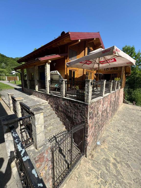 a building with a porch with an umbrella on it at Villa Lavanda in Banja Luka