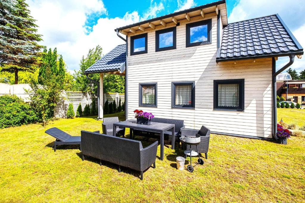 una casa con una mesa y sillas en el patio en Domki Bukowy Las, en Rewa