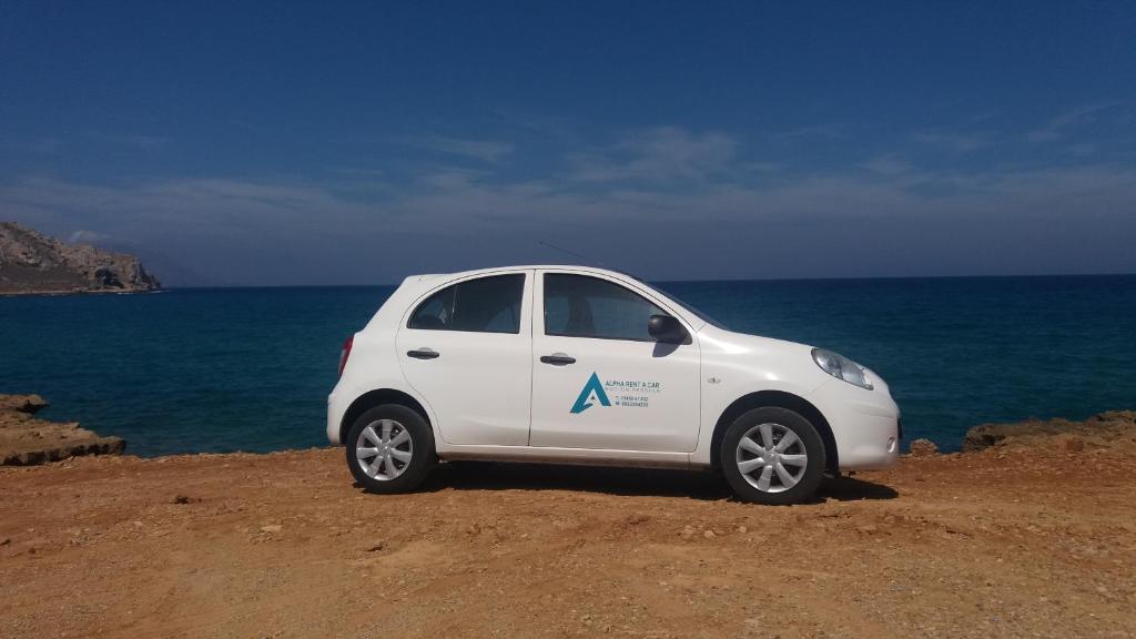 a small white car parked next to the ocean at Alpha Studios in Arkasa
