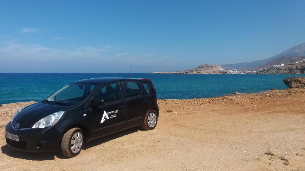 a small black car parked next to the ocean at Alpha Studios in Arkasa