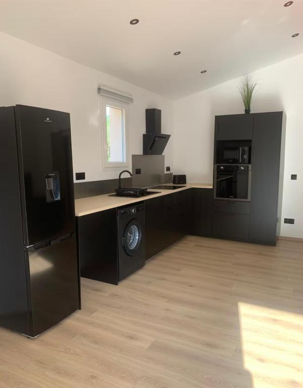 une pièce avec une cuisine avec des armoires et des appareils noirs dans l'établissement Gîte Lavande Luberon, à Saint-Saturnin-lès-Apt