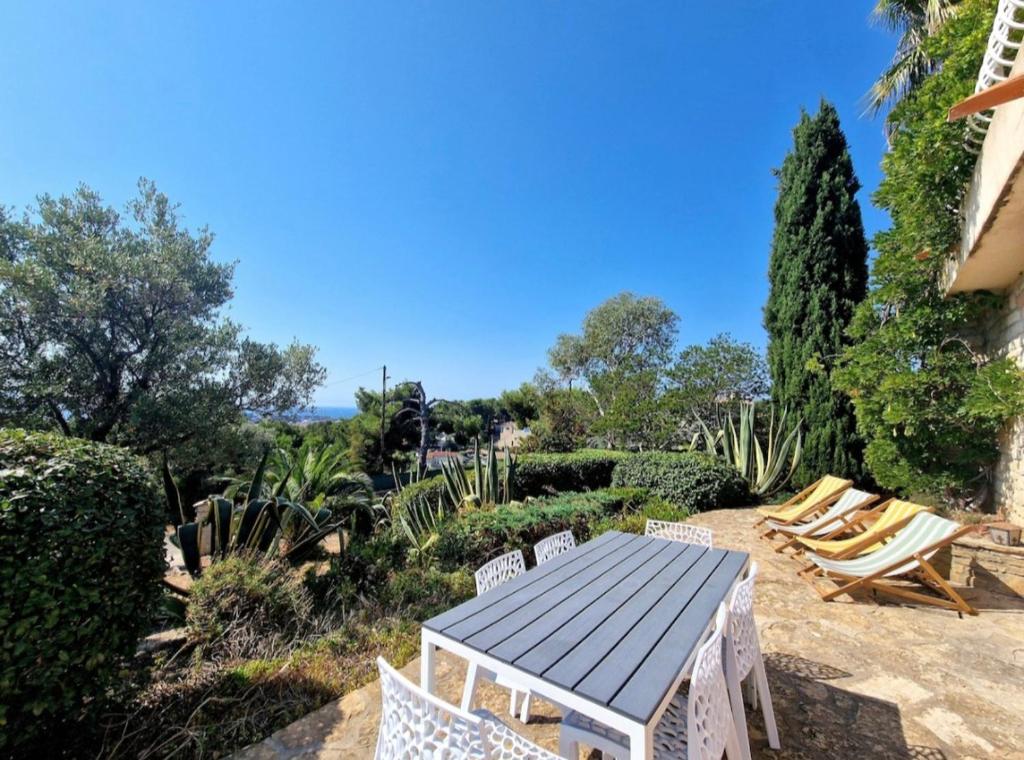 un patio avec une table, des chaises et des arbres dans l'établissement Villa Marguerite T3 vue mer, à Bandol