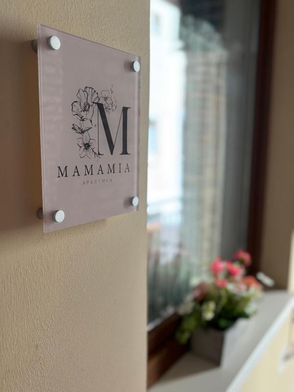 a sign on the wall of a room with a window at Mamamia Apartman in Gyula