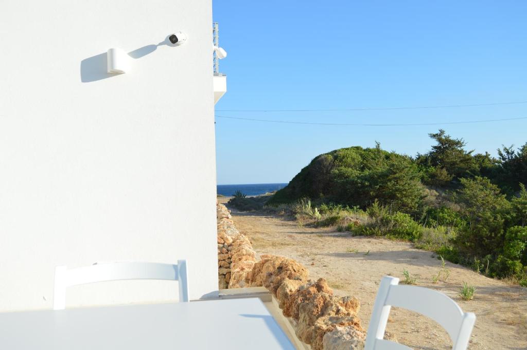 Una habitación con vista a una playa con dos sillas blancas. en Lu rusciu te lu mare, en Maruggio