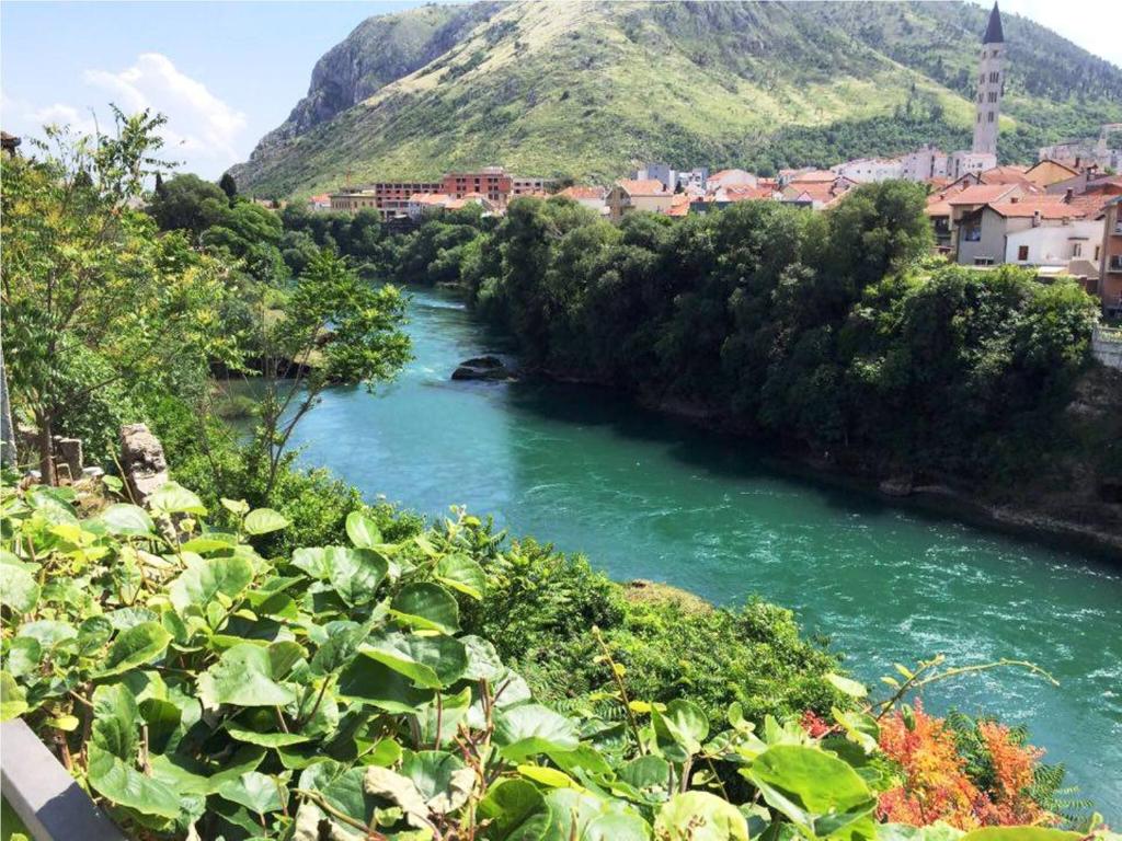 a river with a town and a mountain in the background at Elite Guest House in Mostar