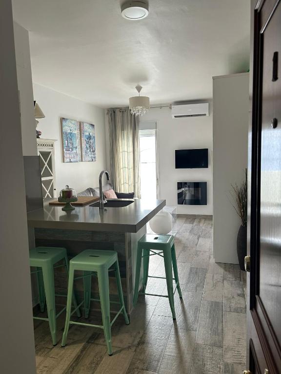 a kitchen with a table and some green stools at Loft Barbate in Barbate